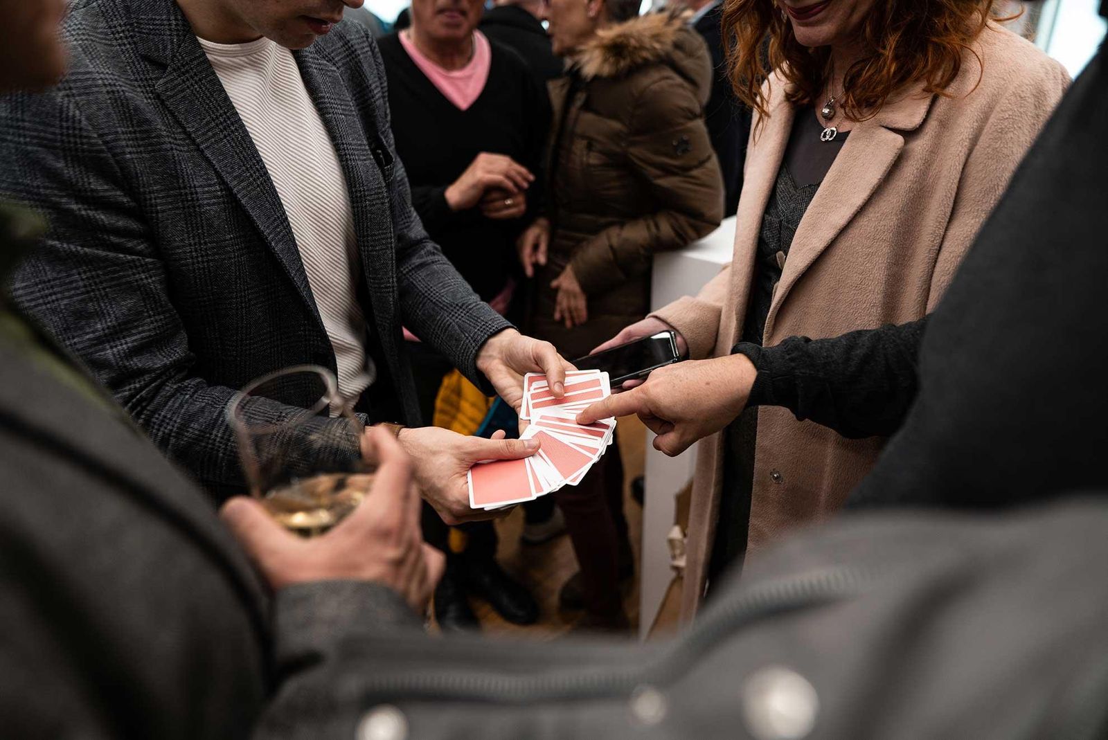 Invitados mirando un juego de cartas de cerca en un cóctel
